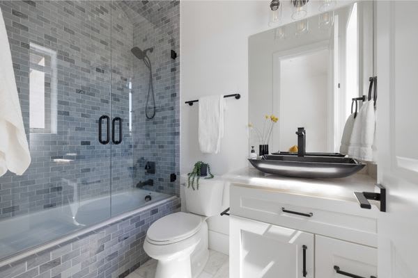 modern white bathroom with tiled shower and black sink